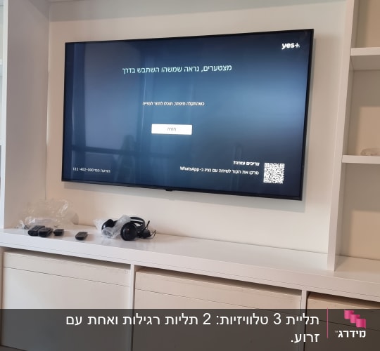 טלוויזיה מותקנת על קיר עם מדפים, אוזניות ושלטים על המדף